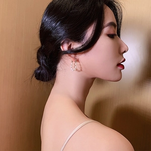 Detail of elegant freshwater pearl hoop earrings worn by a model in warm soft lighting