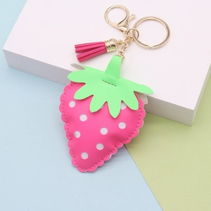Detail of pink strawberry leather keychain with white dots, green leaves and pink tassel