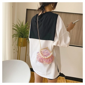Pink sequin shell handbag with pearl handle and chain strap on a female model