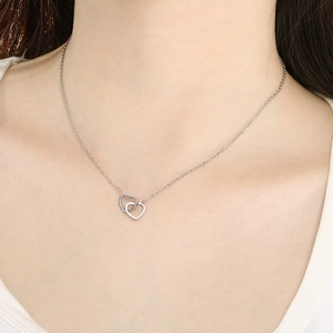 Minimalist silver interlocking double heart pendant necklace worn on a model's neck