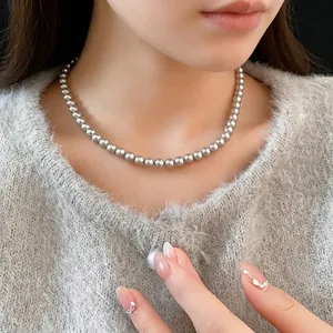Elegant single layer grey pearl necklace worn by a model over a grey knit sweater