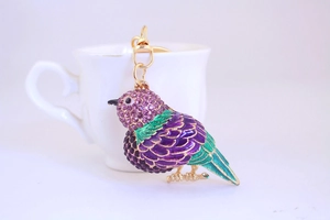 Detailed macro view of a purple and green enamel kingfisher keychain with purple rhinestones