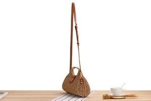 Macro detail of the woven paper rope texture and brown PU leather strap on a seashell bag
