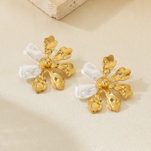 Detail of gold floral earrings with hollow metal petals and white baroque pearls