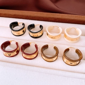 Close-up of four colorful enamel hoop earrings neatly arranged on a jewelry tray