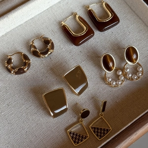 Detail view of retro geometric resin earrings with gold metal frames on linen