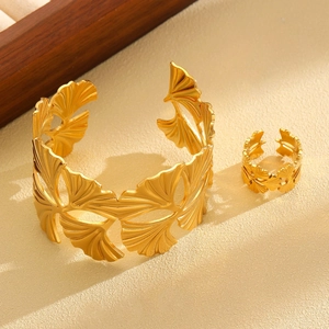 Macro shot of matte gold ginkgo leaf jewelry set with hollowed details on stone backdrop