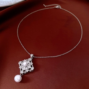 Macro shot of silver filigree pendant featuring white pearls and sparkling zircons