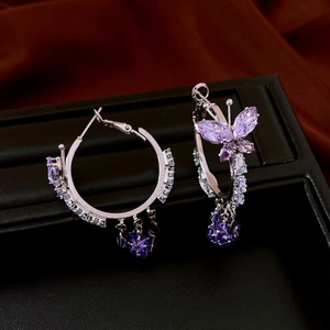 Detailed shot of silver butterfly earrings with purple gemstones on black leather