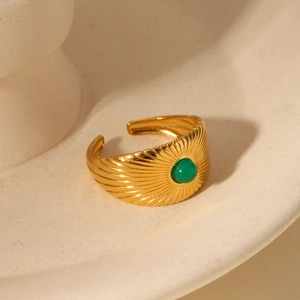 Detailed view of vintage gold ring with green gemstone on cream ceramic holder
