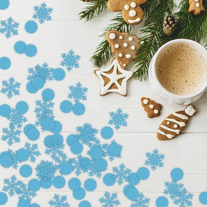 Blue snowflake and round paper confetti scattered on white wood with festive holiday decor