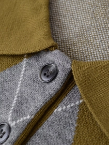 Detail of diamond pattern knit polo with mustard green accents and dark round buttons