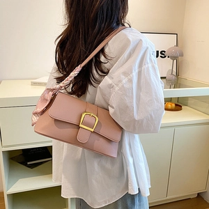 Detail of pink lychee leather handbag with gold D-ring and silk scarf decoration