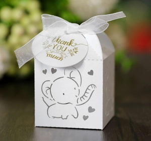 Close-up of white elephant hollow-out wedding candy gift box with ribbon and thank you tag