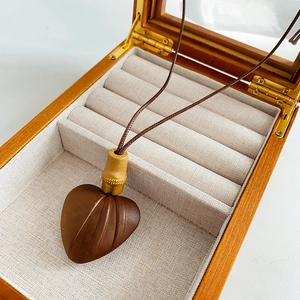 Detail of wooden heart pendant with textured surface and gold connector in a wood jewelry box