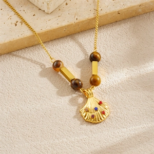 Gold ocean seashell necklace with colorful stones and brown beads on stone surface