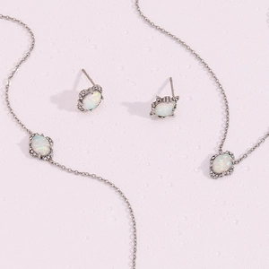 Detail eines silbernen Opal-Schmucksets mit Kristallen auf Wassertropfen-Hintergrund
