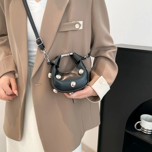 Mini black leather crossbody bag with silver studs and adjustable strap shown on model