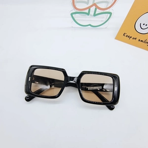 Flat lay of black square hip-hop sunglasses with brown lenses on white background