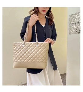 Détail du sac cabas matelassé beige avec bandoulière chaîne et texture en cuir synthétique