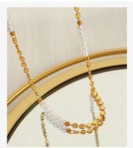 Detailed shot of alternating white pearls and polished gold metal discs on a mirror
