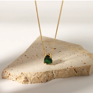 Detail of 18k gold plated necklace with a green pear-cut zircon pendant on stone