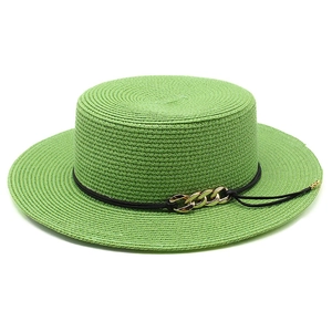Gros plan d'un chapeau de paille vert avec cordon noir et détail de chaîne dorée