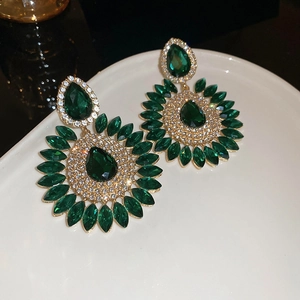 Detail of dark green teardrop crystal earrings with gold trim and white rhinestones