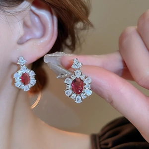 Dettaglio macro di orecchini vintage in argento con zircone rosso e alone floreale bianco