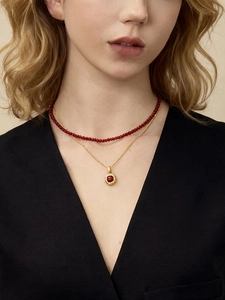 Close-up of double-layered gold plated necklace with red beads and tiger eye pendant
