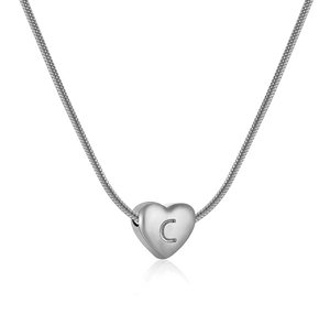 Dettaglio del ciondolo a cuore argento con lettera C su una collana a maglia serpente
