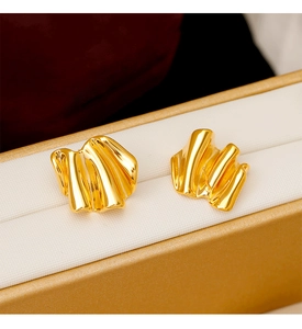 Close-up of golden wavy earrings with high-polished mirror finish in a jewelry box