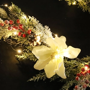 Guirlande de Noël avec magnolias blancs, pommes de pin et lumières LED sur fond sombre