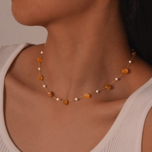 Elegant gold-plated stainless steel necklace with orange stones and white pearls on a model