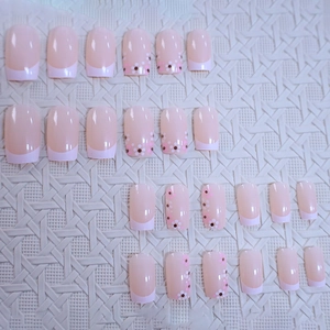 Pink French tip press-on nails with small floral patterns and glossy finish set