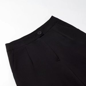 Dettaglio di pantaloni neri con chiusura a bottone singolo, cerniera e tasche laterali