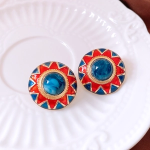 Macro detail of vintage round stud earrings with blue resin gem and red enamel finish