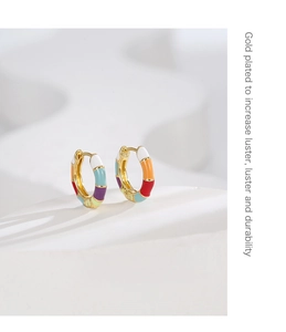 Detail of colorful bamboo style enamel earrings with gold plating on white geometric blocks