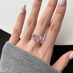 Detailed close-up of a silver ring featuring pink gems heart butterfly design on finger