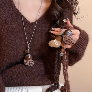 Détail d'un pendentif gland en peluche léopard avec étoile en métal sur un collier long