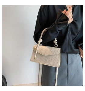 Detail of cream pleated shoulder bag with knot strap and gold metal ring hardware