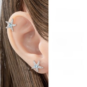 Detail of silver starfish earrings with micro-paved zircons and light blue gems