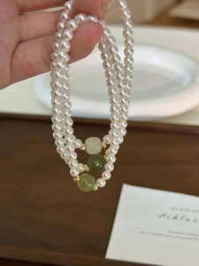 Detail of a three-layered pearl bracelet set with green jade beads and gold accents