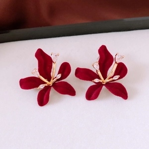 Close-up of red flocked flower earrings with gold metal accents and zircon crystals