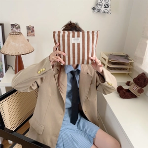 Brown and white striped toiletry bag held by model in a natural home setting