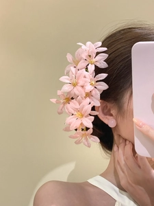 Détail d'une épingle à cheveux fleur en tissu rose et boucles d'oreilles assorties raffinées