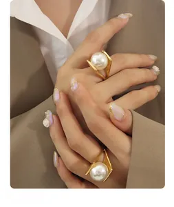 Close-up of minimalist gold titanium ring with a large white pearl worn on a model's finger