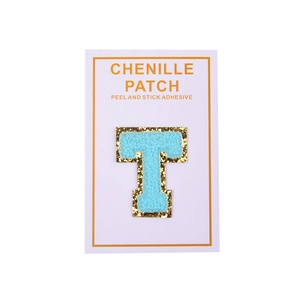 Macro detail of sky blue chenille letter T patch with gold glitter borders and adhesive back