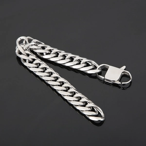 Detailed view of silver Cuban link chain bracelet with secure buckle on reflective black surface