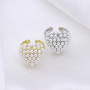 Detailed view of adjustable heart-shaped pearl rings in gold and silver on silk